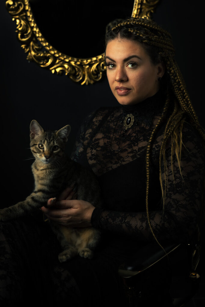 Fine art portrait of a woman with braided hair holding a tabby cat, photographed by Austin, Texas portrait photographer Javier Shirley.